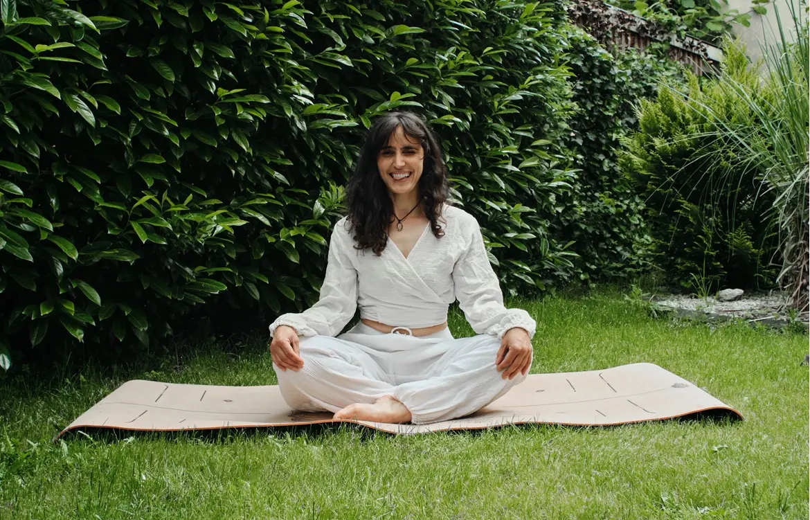 Gerta seated on her yoga mat outdoors